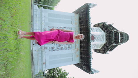 woman in a pink dress posing in front of an ornate pagoda