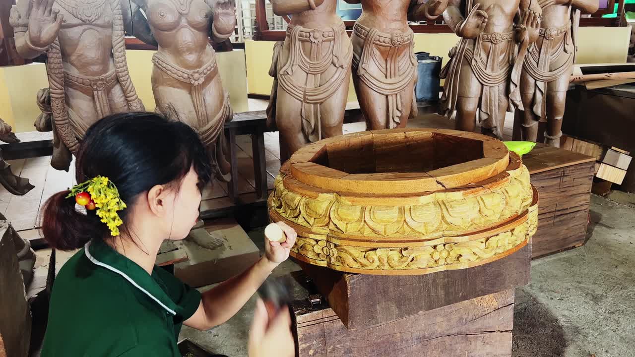 sculpturing the circular wooden piece by a woman in thailand