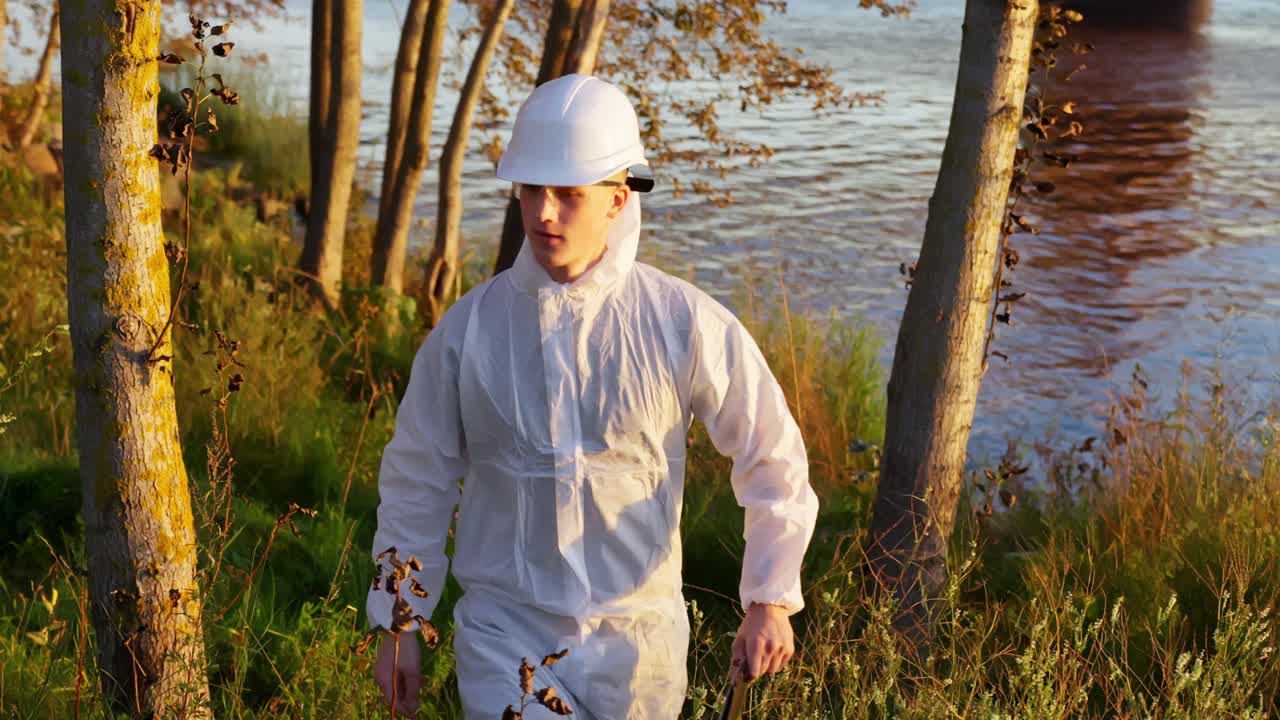 Inspector medioambiental de pie cerca del arroyo de un bosque, supervisando la salud y la seguridad del ecosistema
