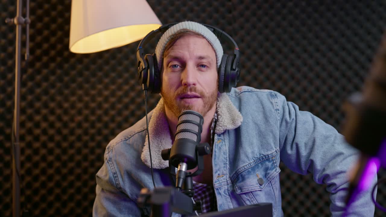 Podcaster wearing headphones attentively listens and nods to guest in a studio setting. Focus, active listening, conversation, and professional broadcasting. Media, interviews, content creation.