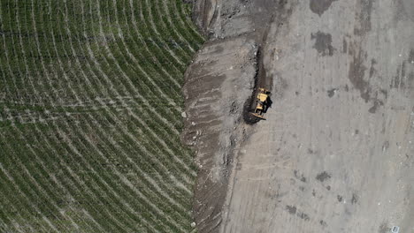 yellow bulldozer moving sand to the side of the field