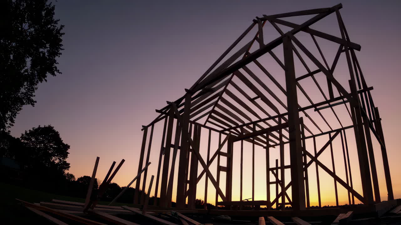 Wooden House Frame Under Construction at Sunset