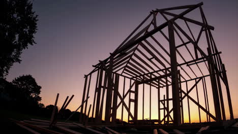wooden house frame under construction at sunset