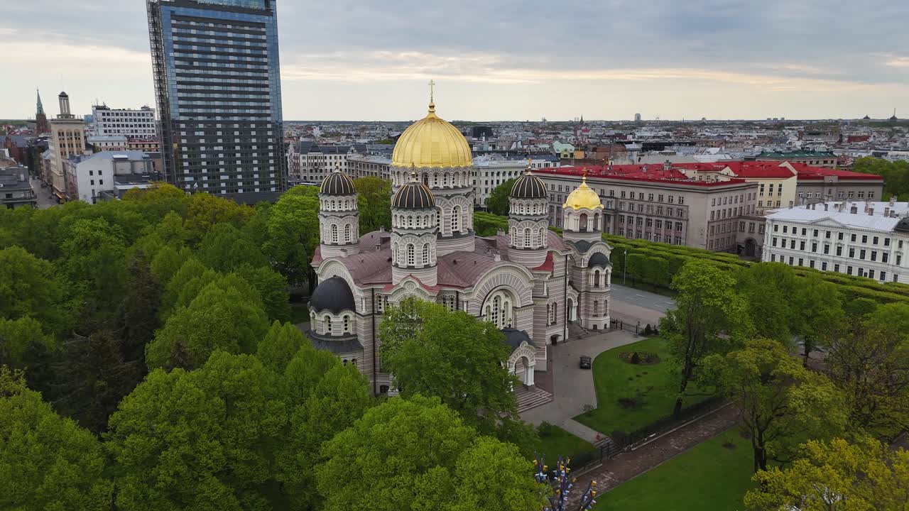 Golden domed church in Riga park, peaceful spring day with city skyline view