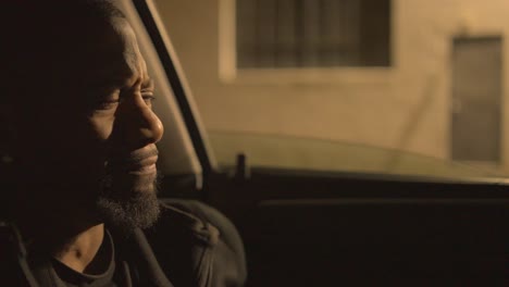 a-black-man-sitting-in-the-drivers-seat-of-a-car-at-night-outside-a-warehouse-is-clearly-distressed-and-evaluating-his-decisions