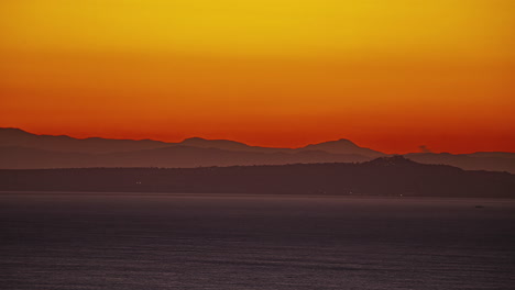 Mountain-landscape-with-city-lights-bellow-and-bright-sun