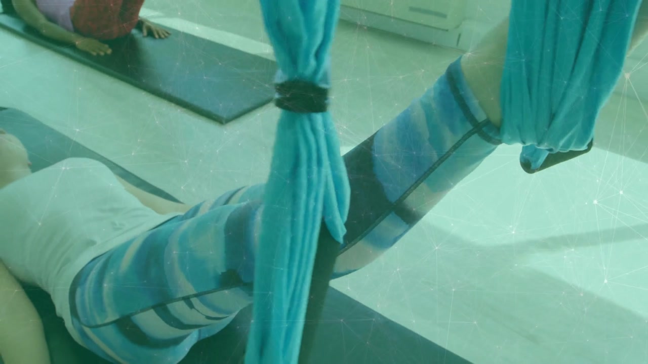 Woman hooking legs into aerial silks lifting lowering unthreading legs for alignment in yoga studio