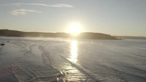 Panning-Aerial-Truck-Shot-Von-Bantham-Beach-Bei-Sonnenaufgang-Mit-Dampf,-Der-Aus-Dem-Ozean-Aufsteigt