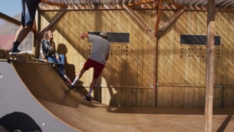 video of happy diverse female and male skateboarders training in skate park