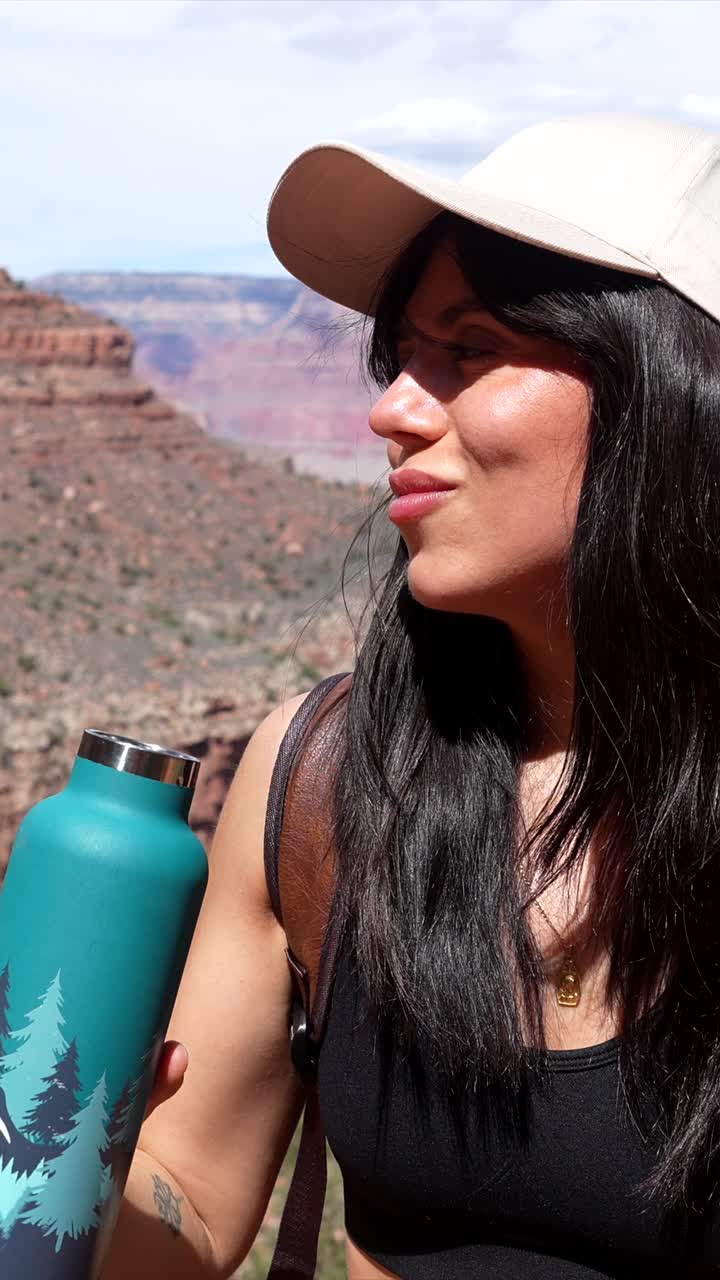 Giovane donna che beve acqua da una bottiglia in un canyon desertico