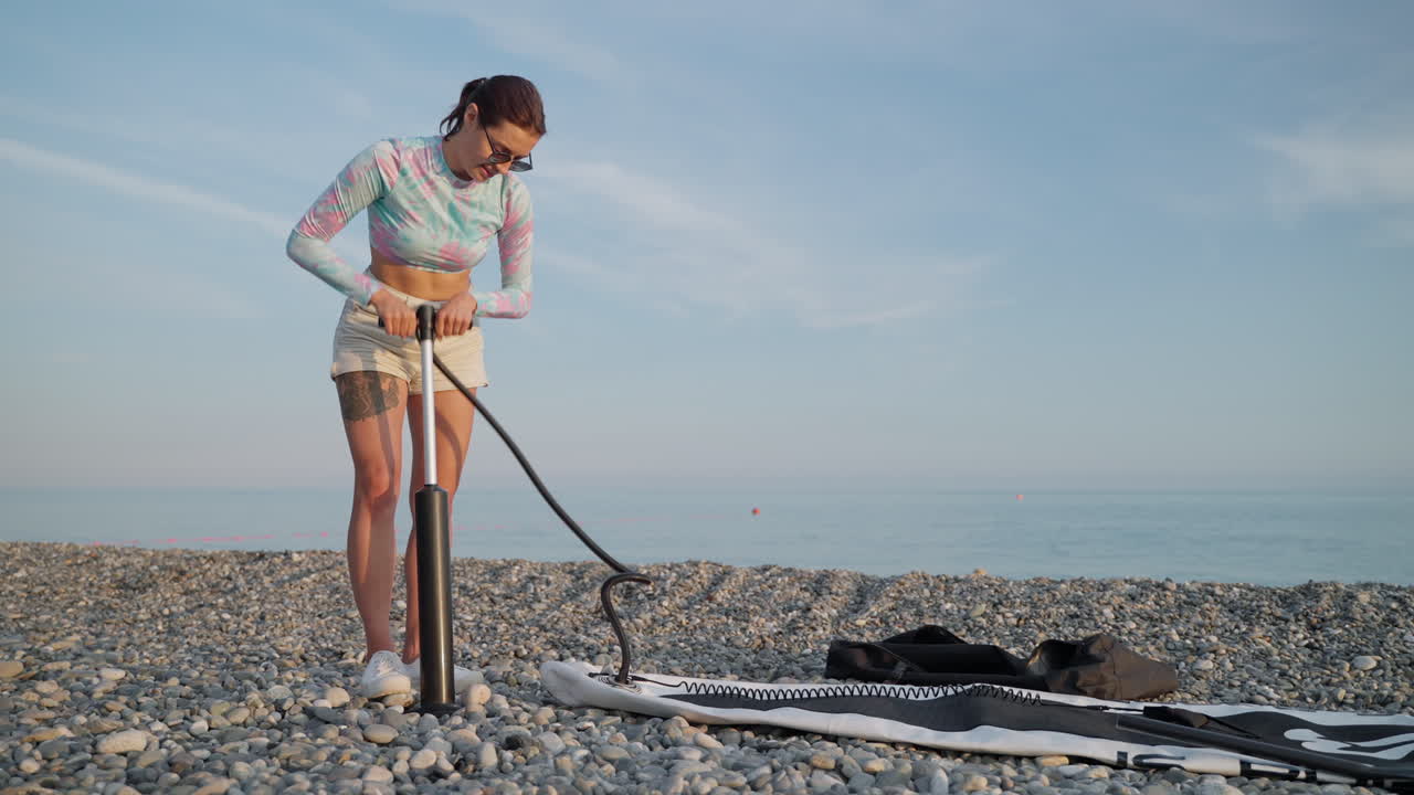 해변 에서 부풀어올릴 수 있는 스탠드업 패들보드 를 준비 하는 여자