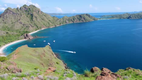 Lancha-Rápida-Que-Se-Desplaza-A-Través-Del-Agua-Azul-Turquesa-Del-Océano-Verde-Desde-La-Idílica-Bahía-Aislada-De-La-Isla-Tropical-De-Padar-En-El-Parque-Nacional-De-Komodo,-Al-Este-De-Nusa-Tenggara,-Indonesia