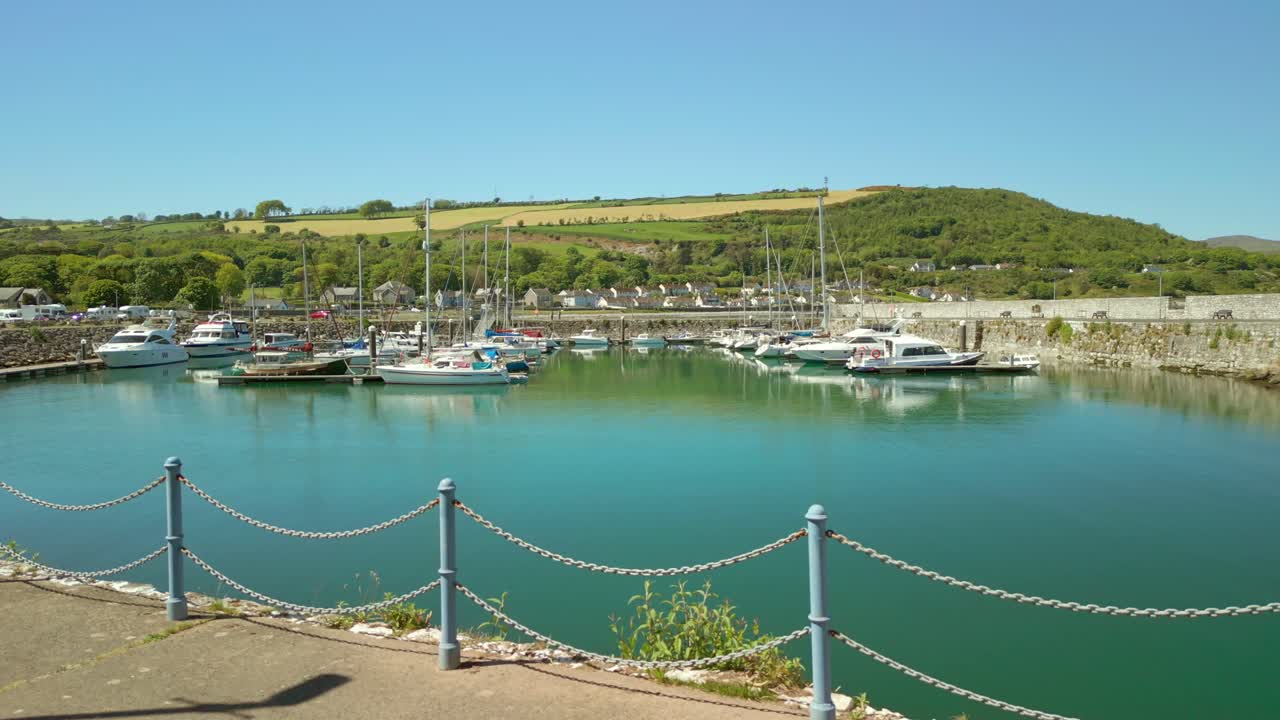 Low, advancing aerial video of the boats at Glenarm Bay, on the Causeway Coastal Route in Northern Ireland, on a bright and sunny day. Filmed in 4K, 60FPS and with Rec709 color.