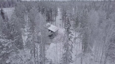 Vista-Aérea-Moderna-Cabaña-De-Invierno-En-La-Colina-En-El-Bosque-Nevado-Del-Norte,-Escena-Navideña-Y-De-Vacaciones-De-Esquí