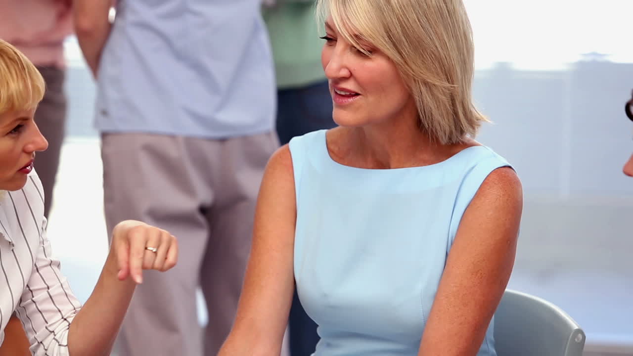 mujer de negocios tomando notas mientras otros hablan