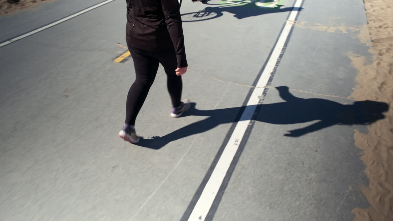 Woman in black taking a stroll on the cycle lane of the beach of Santa Monica beach