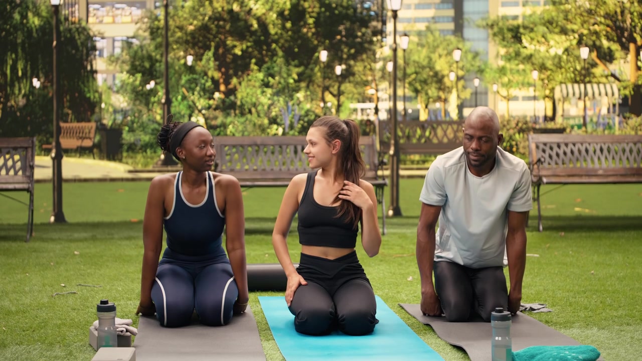 Istruttrice di yoga in posizione di piegamento in avanti da seduta con le ginocchia al petto su un tappetino