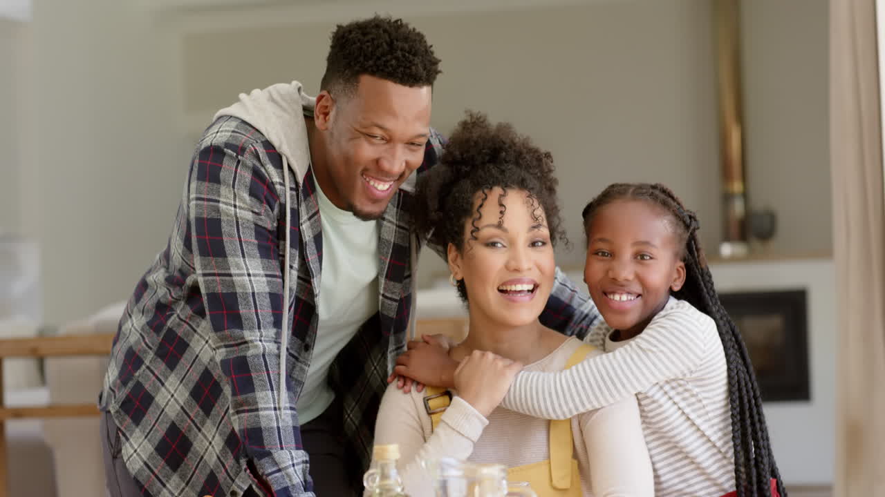 幸せなアフリカ系アメリカ人の両親と娘が自宅で抱きしめ合っている肖像画スローモーション