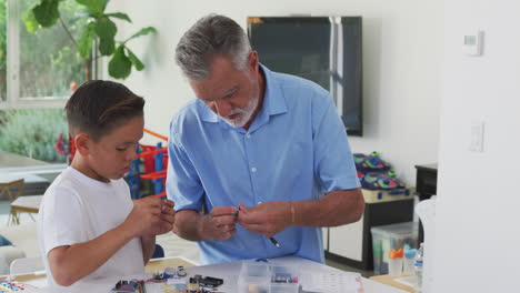 el nieto hispano y el abuelo construyendo un robot de componentes electrónicos en casa juntos