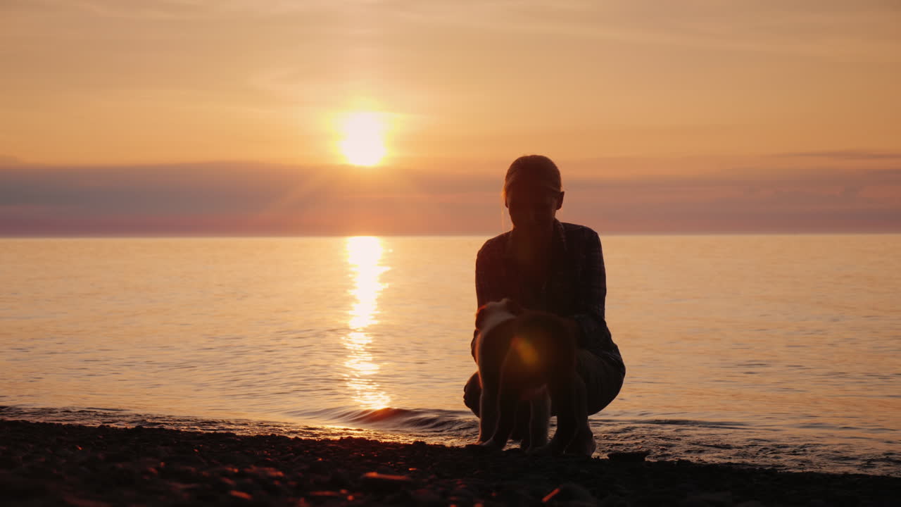 mujer jugando con un perro junto al lago al atardecer