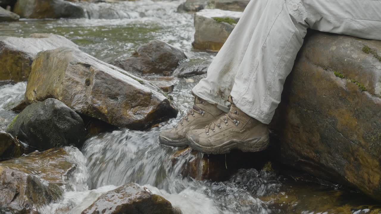 Person sitting by a mountain stream