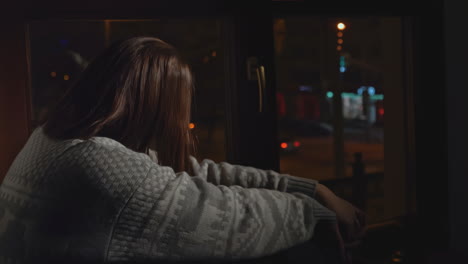 woman sitting by window at night