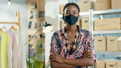 African-American-woman-designer-in-black-mask-looking-at-camera-in-positive-mood-in-clothing-store