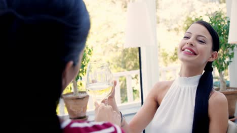 Two-female-friends-toasting-glasses-of-wine-in-restaurant