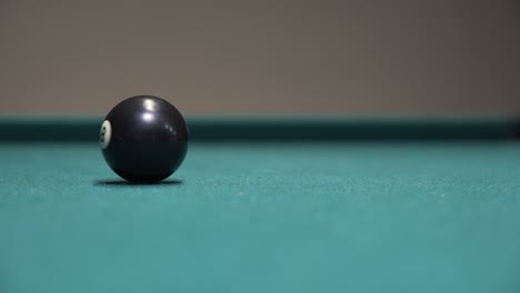 black 8-ball spinning and rolling to a stop on a billiards table