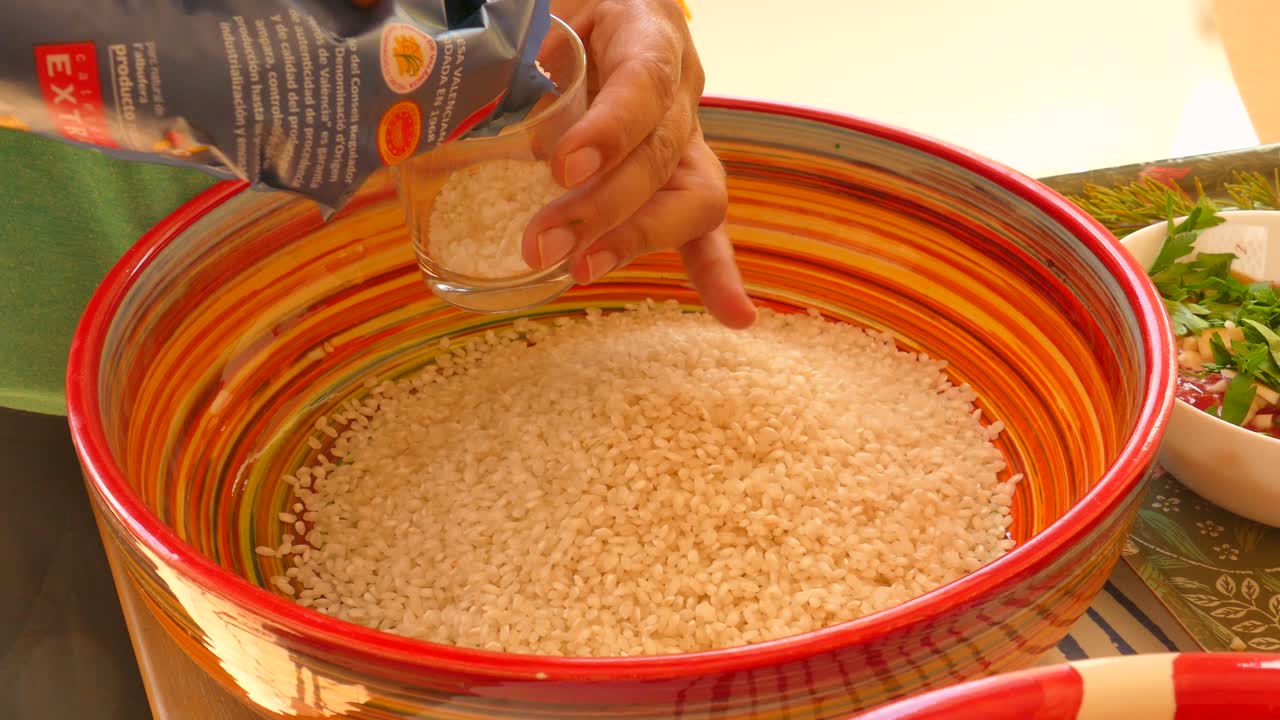 fotografía de cerca del arroz bomba medido y vertido en un cuenco de colores antes de hacer la paella, un plato tradicional español