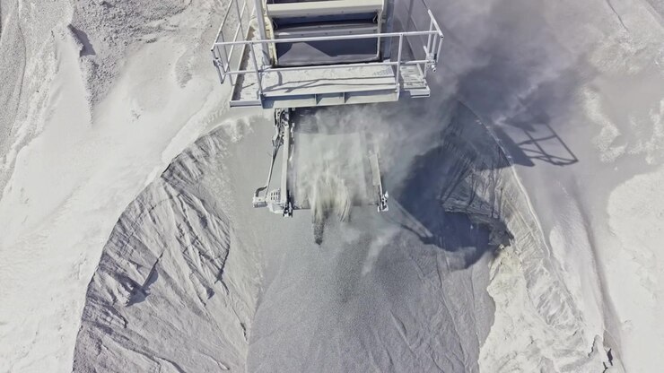Heavy machinery operates at a quarry site to extract materials from the ground in a large, open area during daylight hours