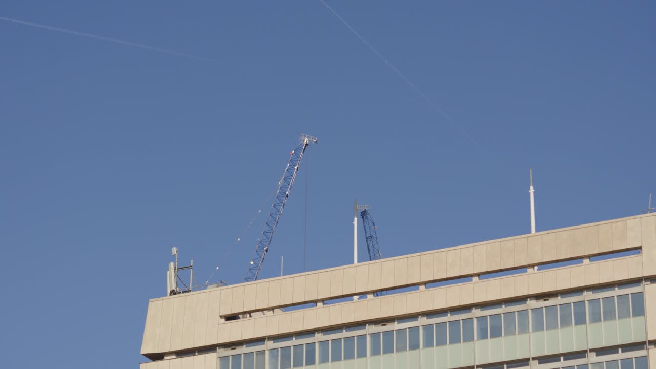 Grúa elevándose sobre un edificio que construye nuevas propiedades inmobiliarias. Fondo de horizonte urbano minimalista que representa el crecimiento de la ciudad y la planificación futura. Londres, Reino Unido