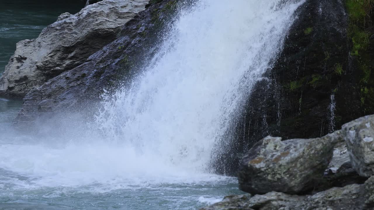 A powerful waterfall cascades over rocks in Queenstown, New Zealand, captured with dynamic movement and natural lighting