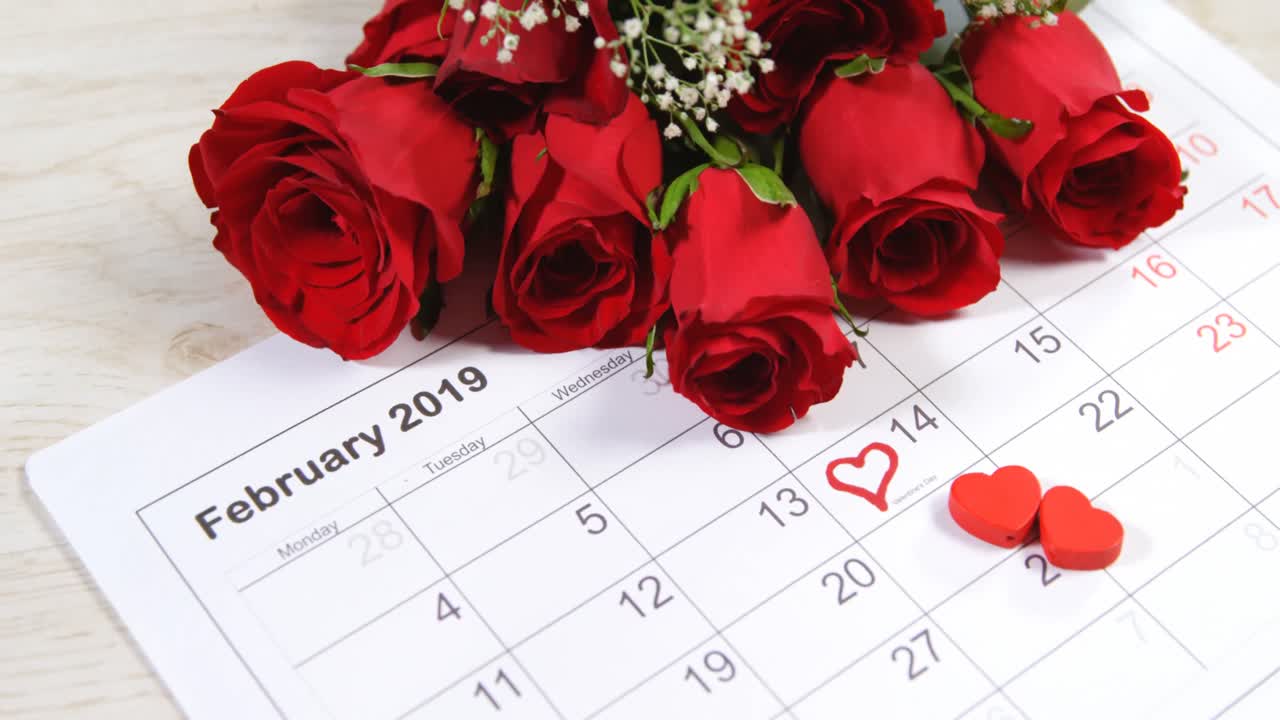 ramo de rosas rojas en el calendario que muestra el 14 de febrero 4k