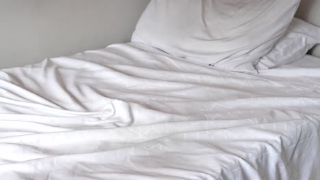 unmade bed with white sheets and pillow