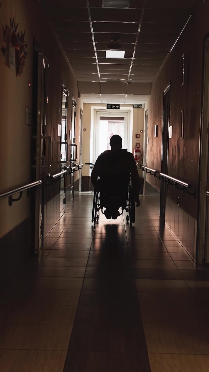 Persona in sedia a rotelle che si muove lungo un corridoio d'ospedale