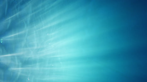 visualización de pantalla de formato vertical: haces de luz solar en bucle que brillan a través del agua azul turquesa cristalina profunda que causa hermosas cortinas de luz con burbujas de aire que se elevan hasta la superficie del agua