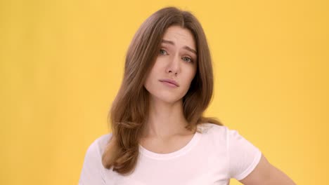 mujer con expresión neutral contra un fondo amarillo