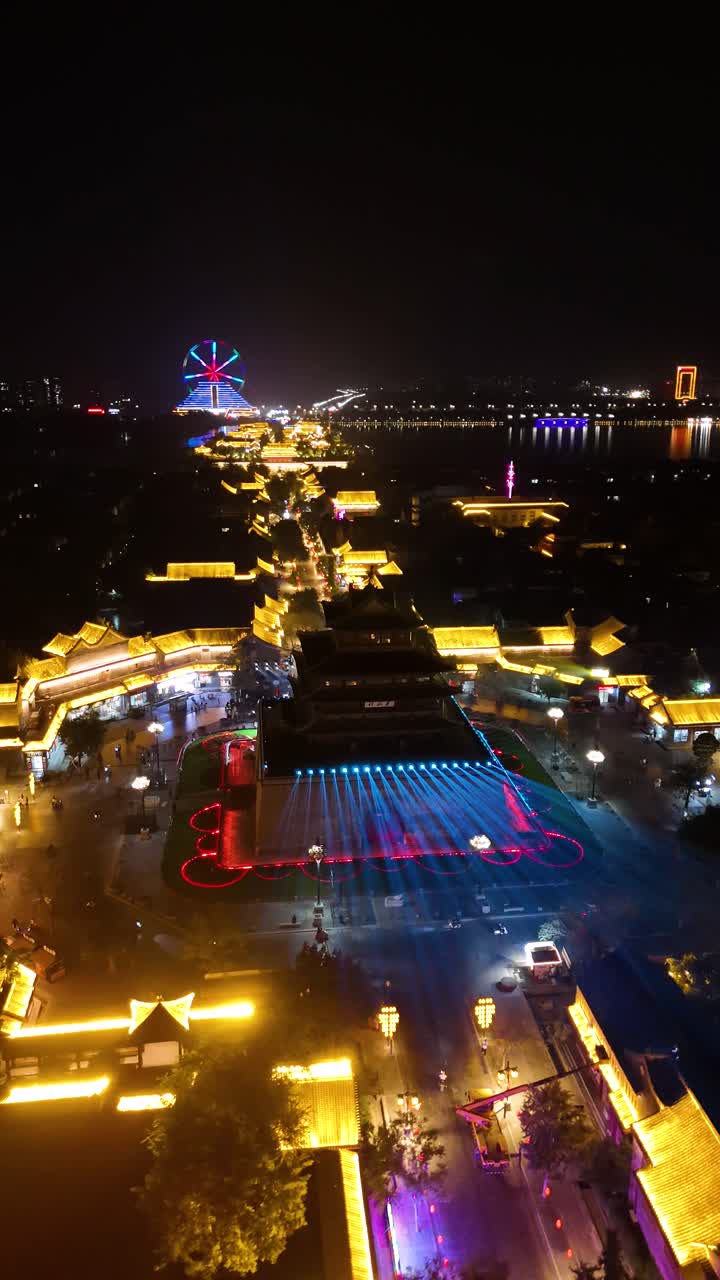 A vertical aerial shot of Liaocheng City in Shandong Province, China. View of Guangyuelou Tower, which is illuminated against the dark sky.