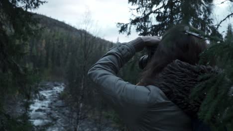 mujer tomando fotografías en el bosque junto al río
