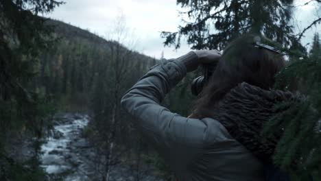 woman taking photograph in forest by river