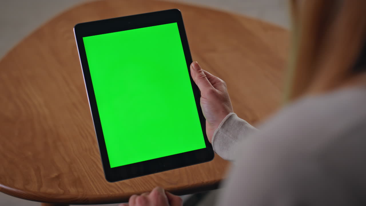 Hands swiping green screen tablet in apartment close up. Woman touching mockup