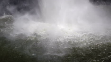 base of powerful waterfall throws up mist from plunge pool water