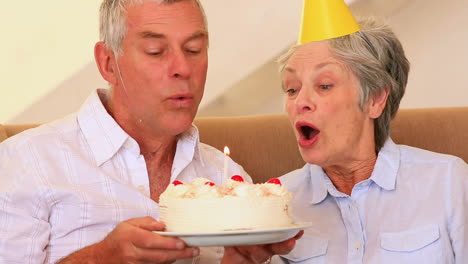 Senior-couple-sitting-on-couch-celebrating-a-birthday