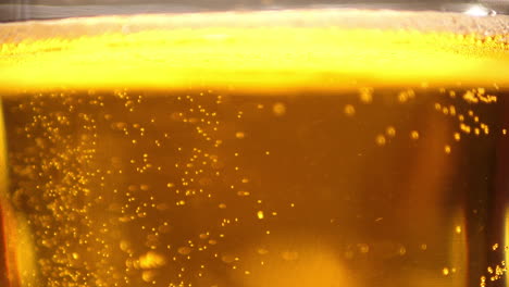 extreme close up of craft beer bubbles floating to the top of a pint glass with foam