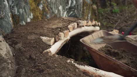 Shoveling-Soil-Onto-Raised-Garden-Bed-Made-Of-Tree-Woods