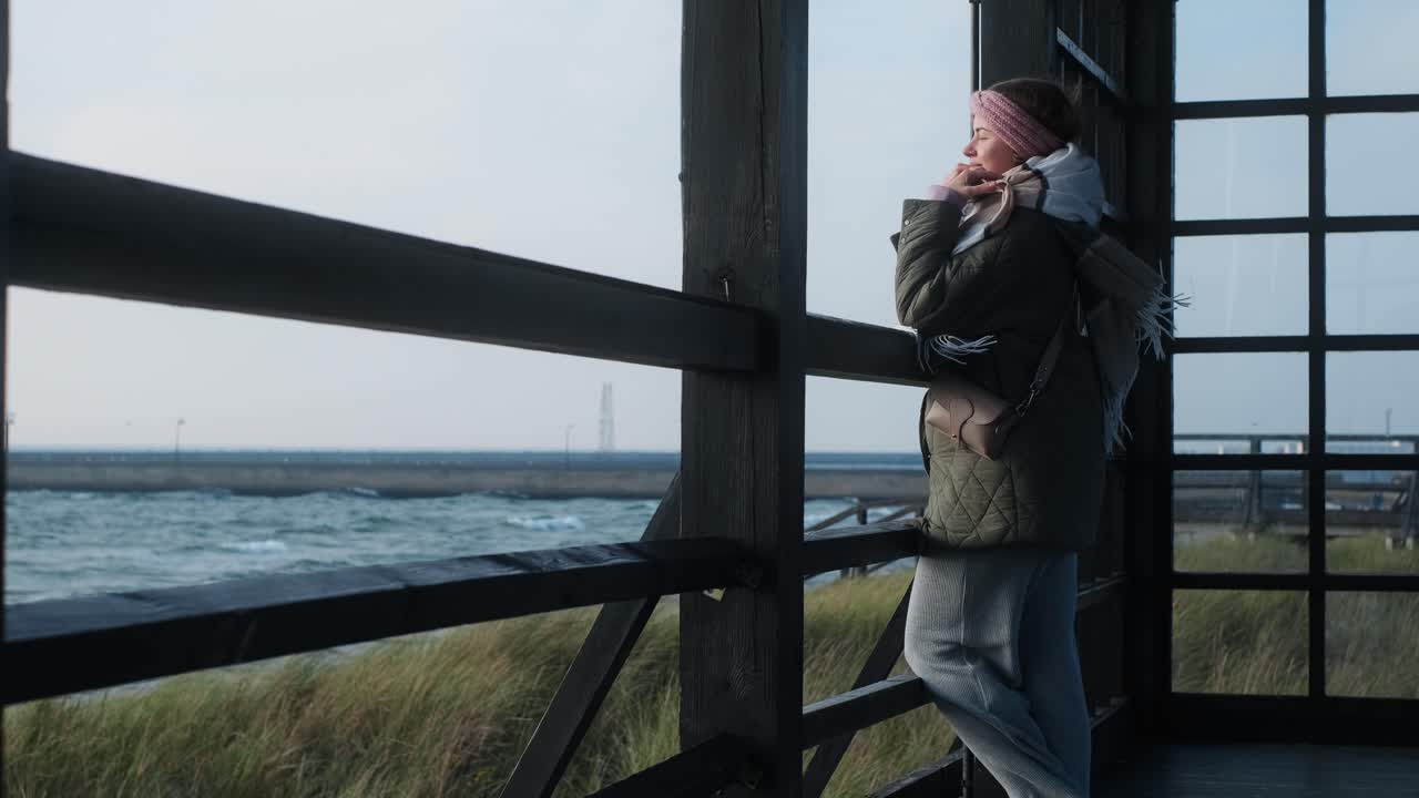 Woman gazing at the sea from a wooden gazebo