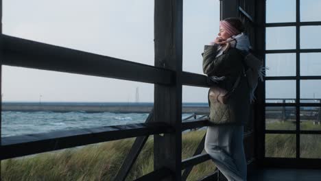 woman gazing at the sea from a wooden gazebo