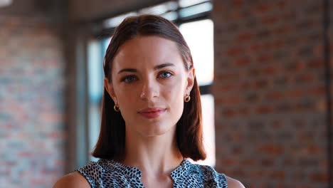 Head-And-Shoulders-Portrait-Of-Serious-Young-Businesswoman-Standing-In-Office