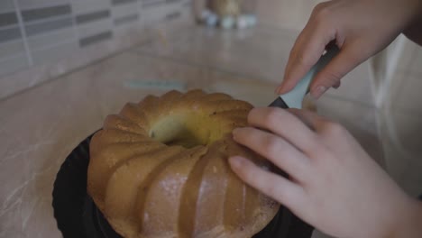 young woman slicing marble bundt cake with kitchen knife